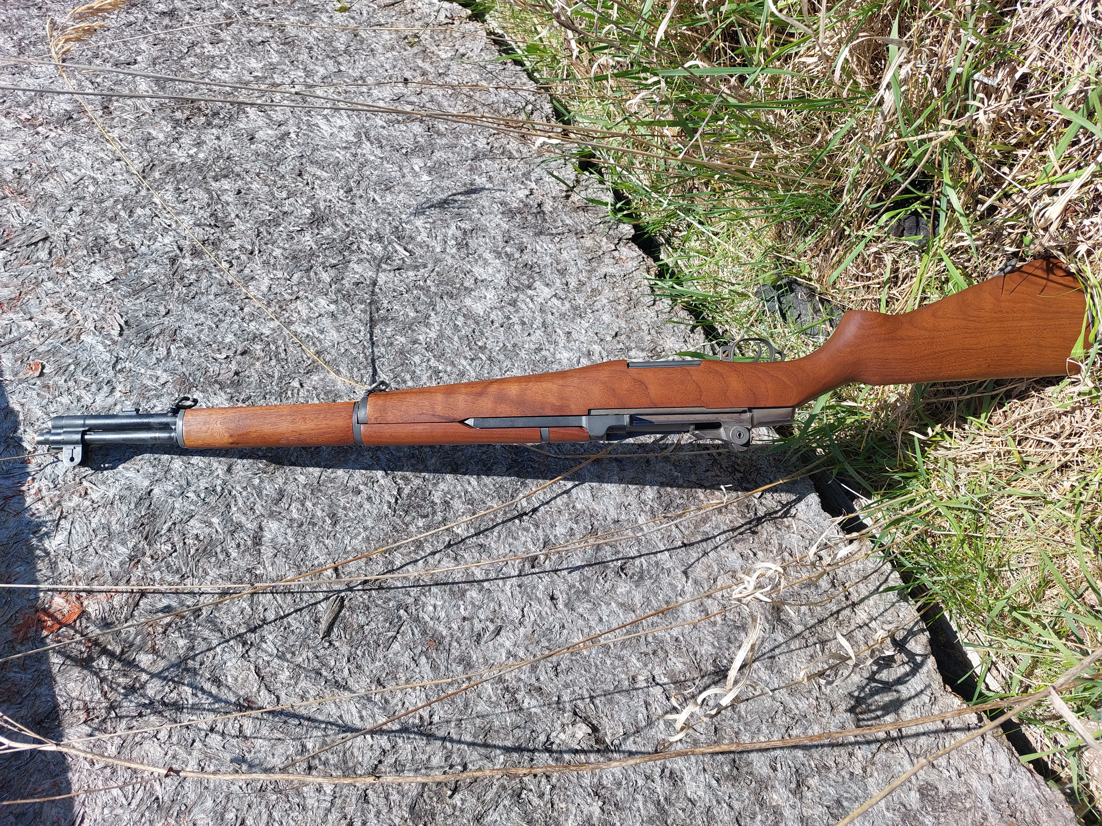 A vintage rifle leaning against textured rock outdoors.